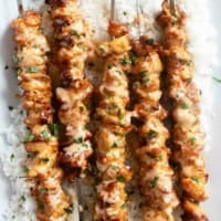 Bang Bang Chicken Skewers over rice on a platter.