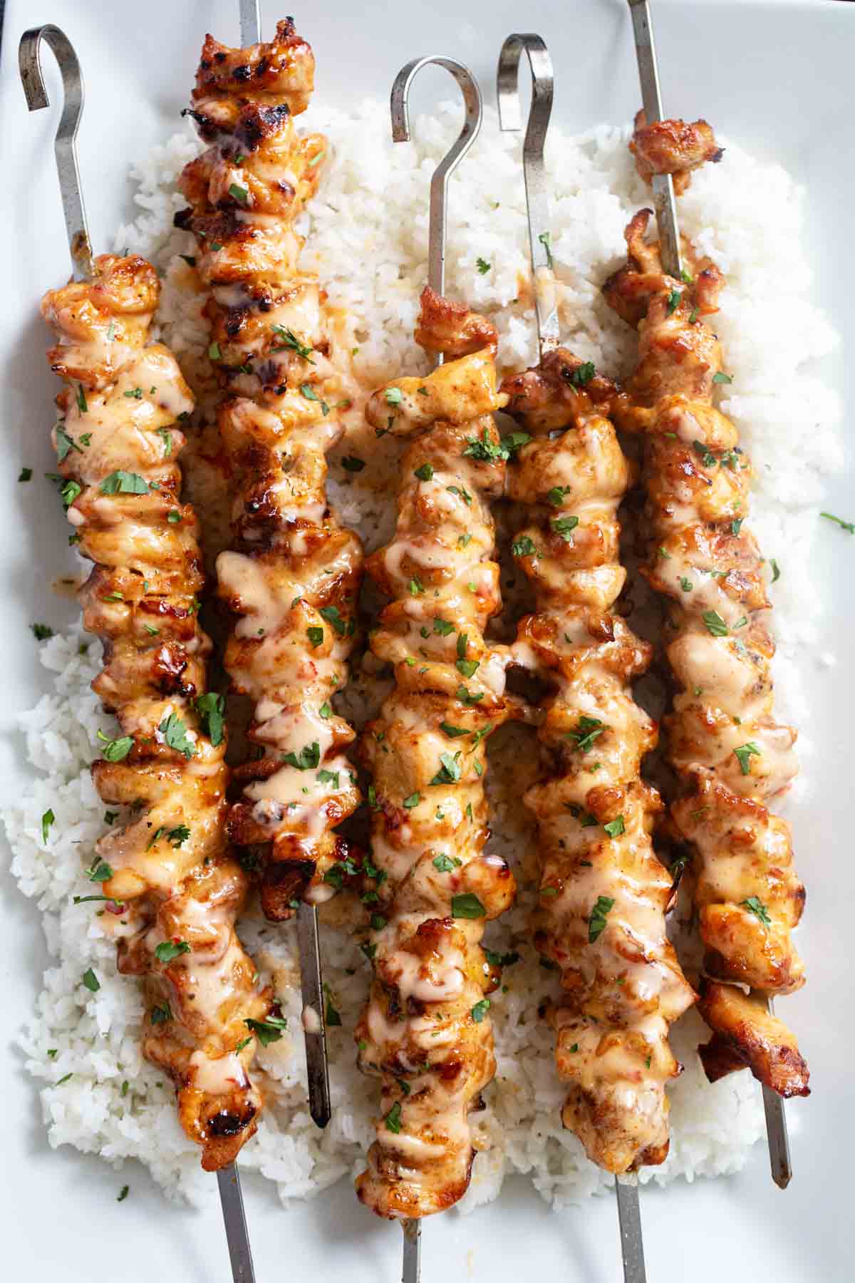 Bang Bang Chicken Skewers over rice on a platter.