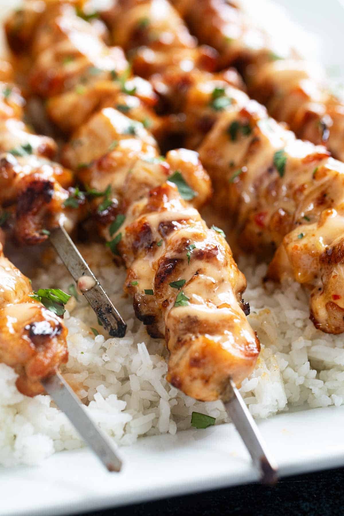 Bang Bang Chicken Skewers topped with cilantro.