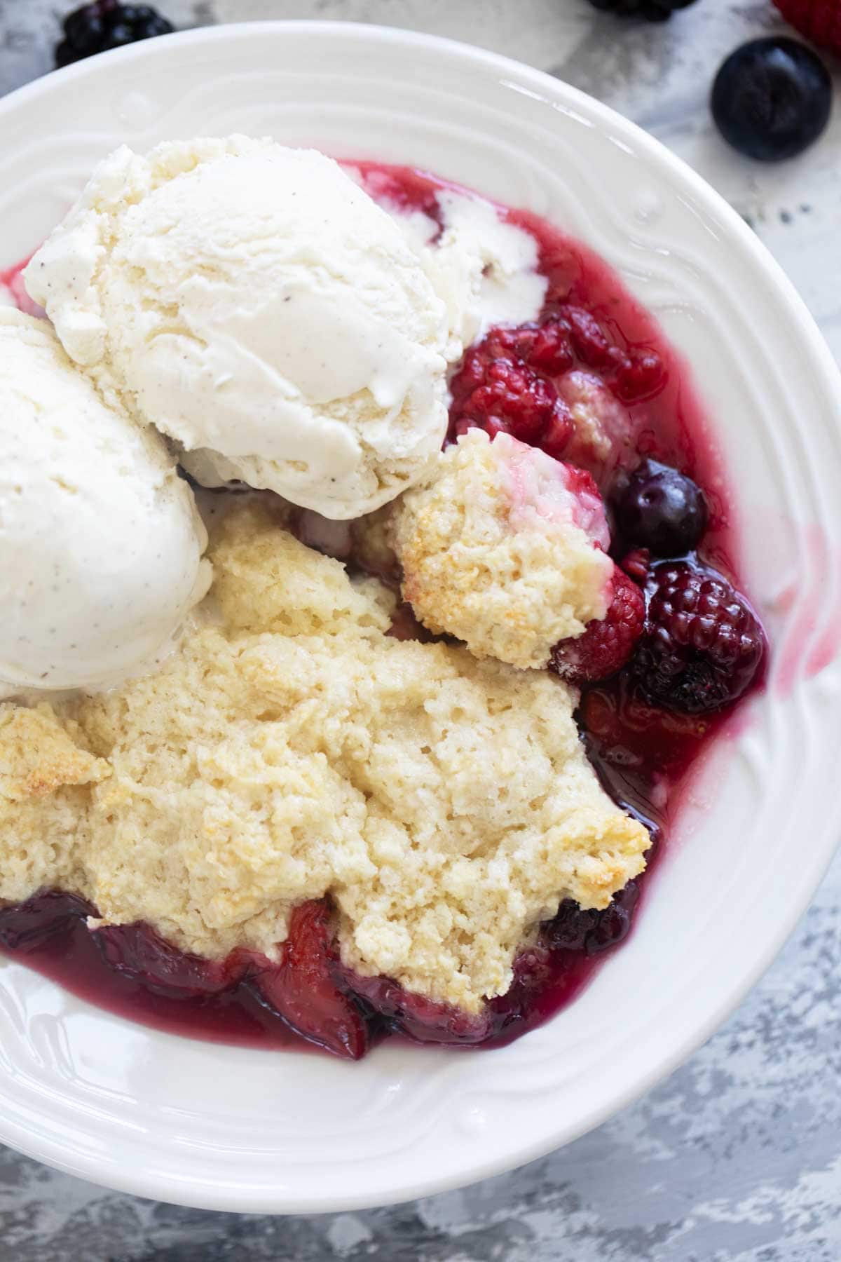 Bowl of berry cobbler with ice cream on top.