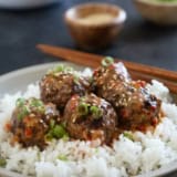Firecracker Meatballs over rice, topped with green onions and sesame seeds.