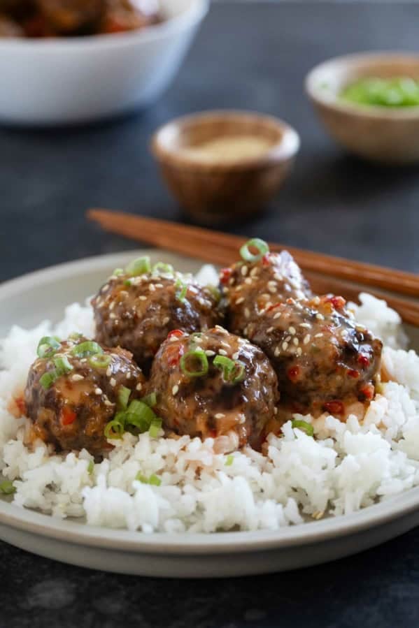 Firecracker Meatballs over rice, topped with green onions and sesame seeds.