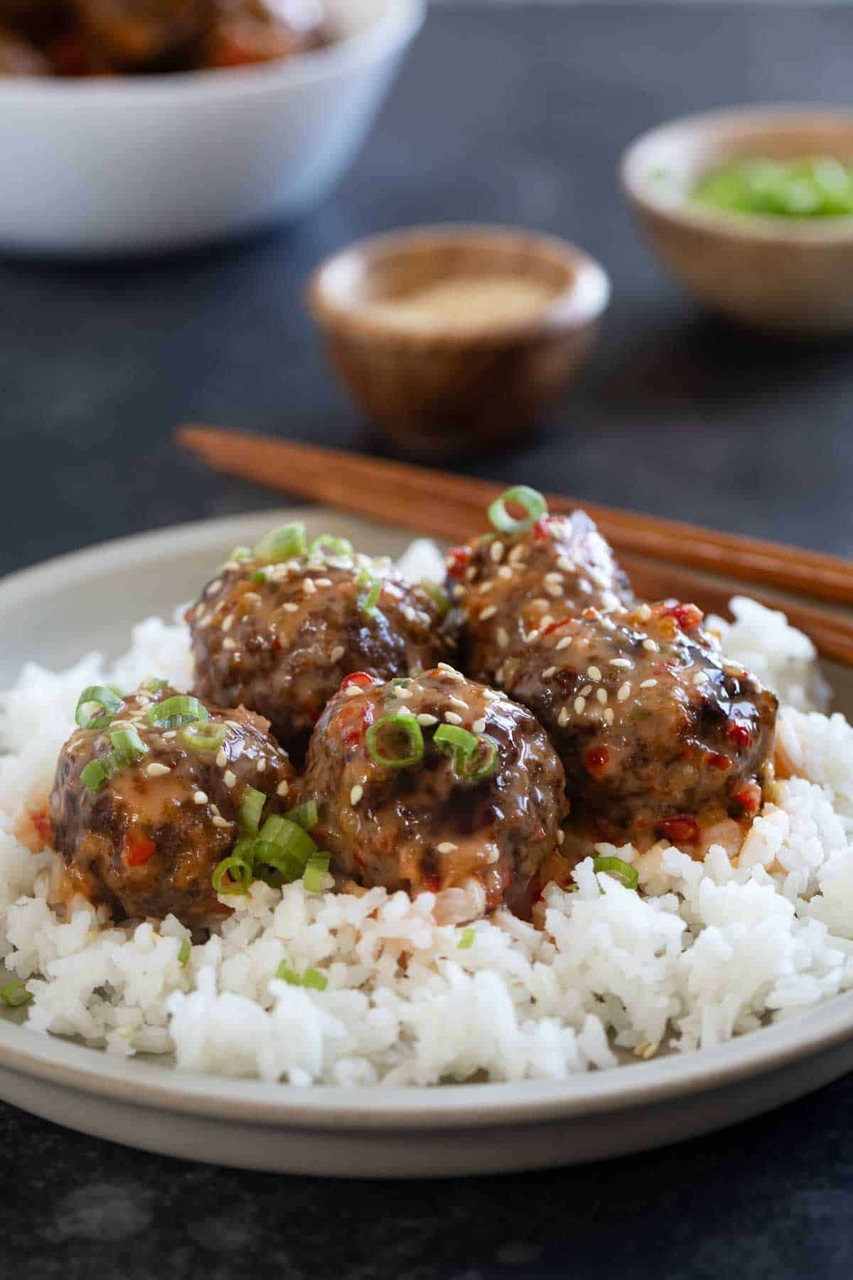 Firecracker Meatballs over rice, topped with green onions and sesame seeds.