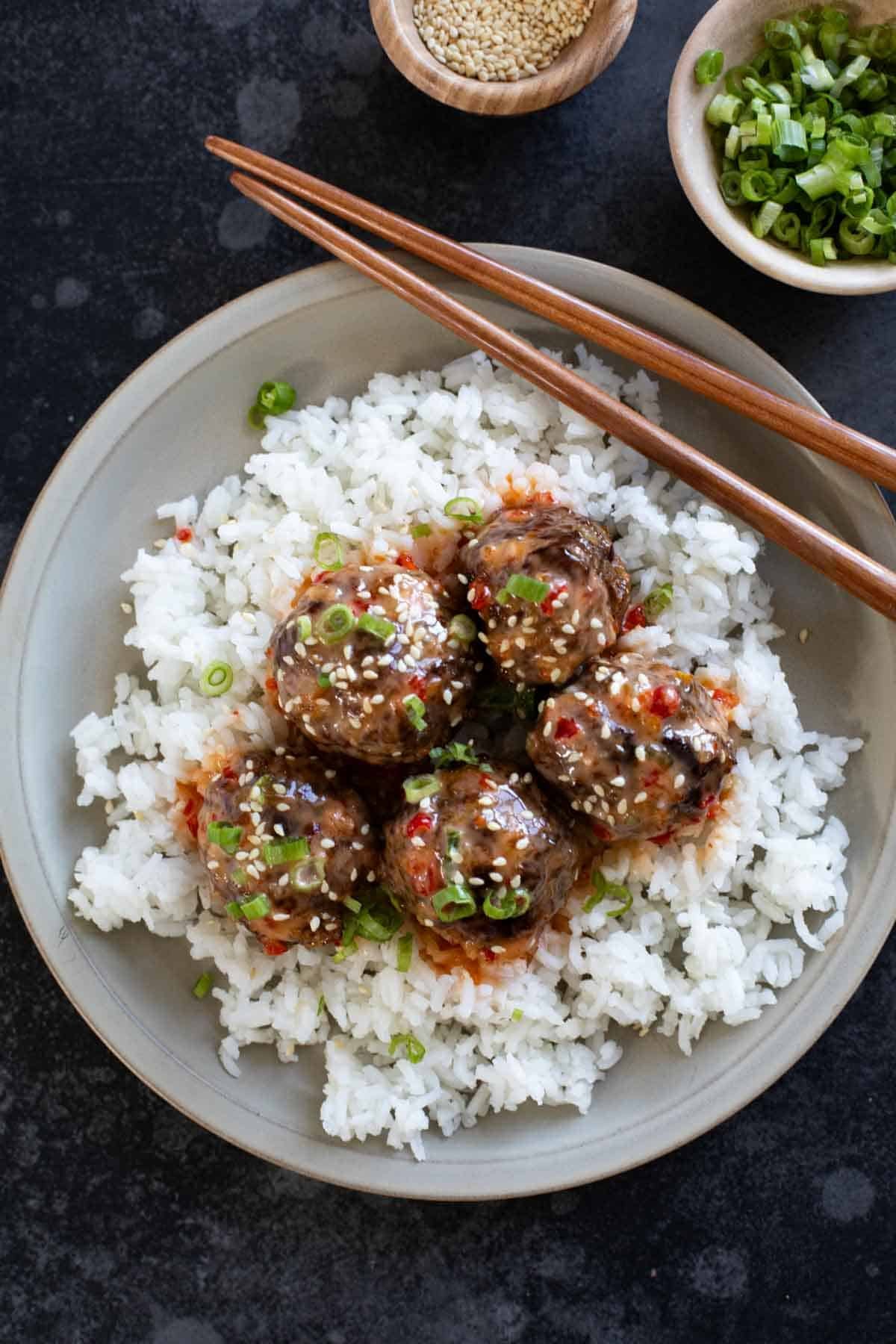 Firecracker Meatballs over rice on a plate.