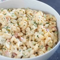 Bowl filled with macaroni salad with celery, peppers, eggs, and more.