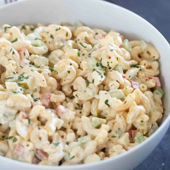 Bowl filled with macaroni salad with celery, peppers, eggs, and more.