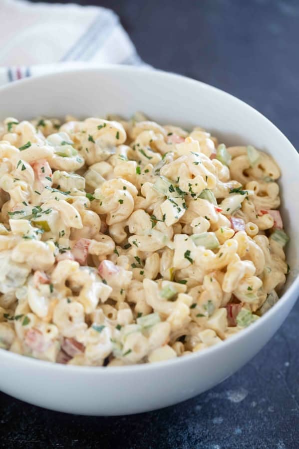 Bowl filled with macaroni salad with celery, peppers, eggs, and more.