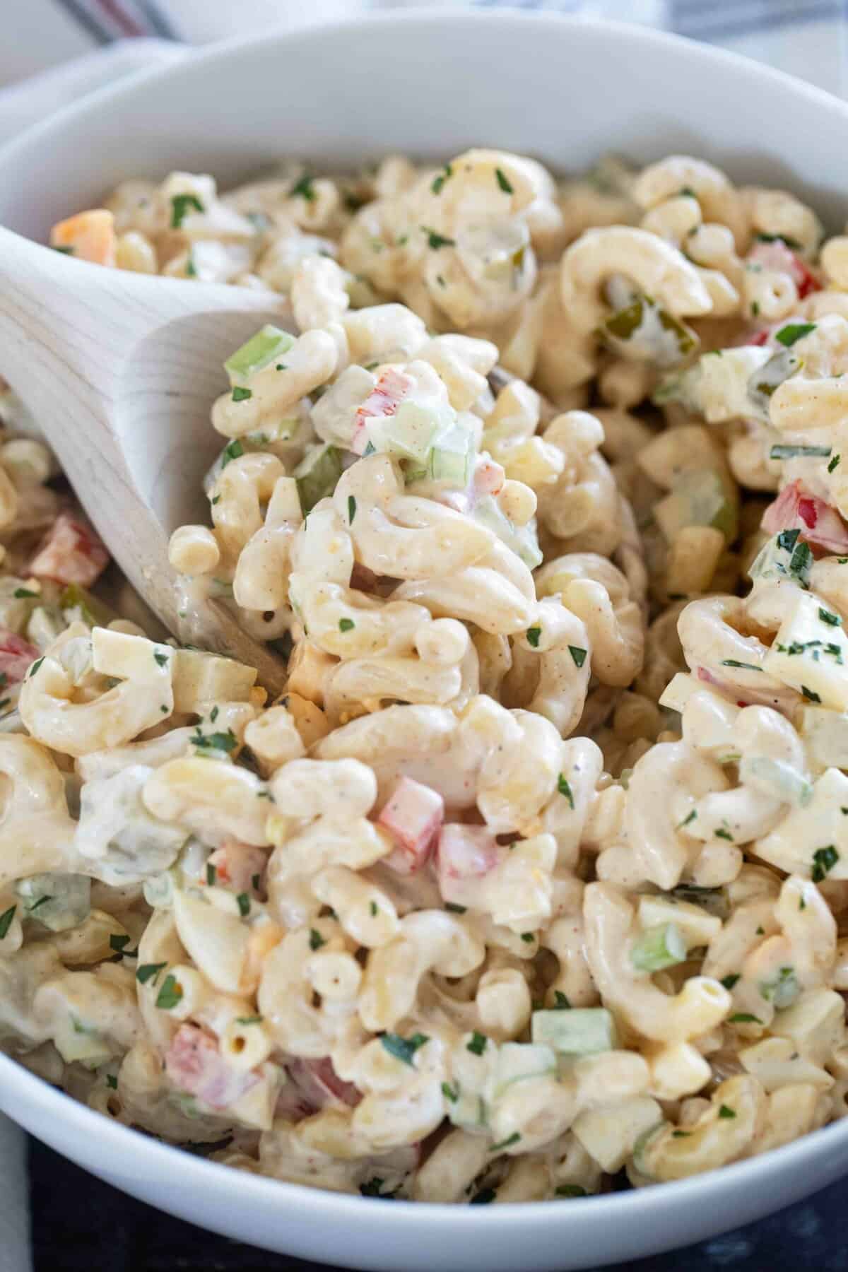 Bowl of macaroni salad with a wooden spoon.