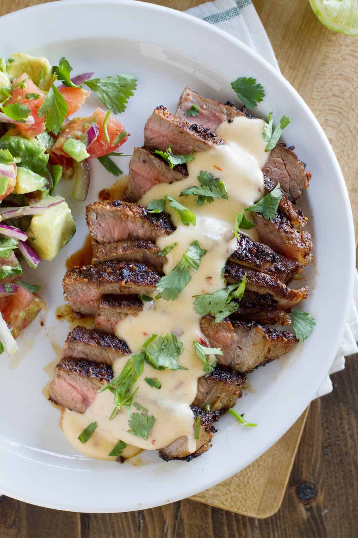 Sliced steak with Mexican spices, with Chile con queso served on top.