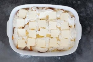 Adding butter to the top of peach dump cake.