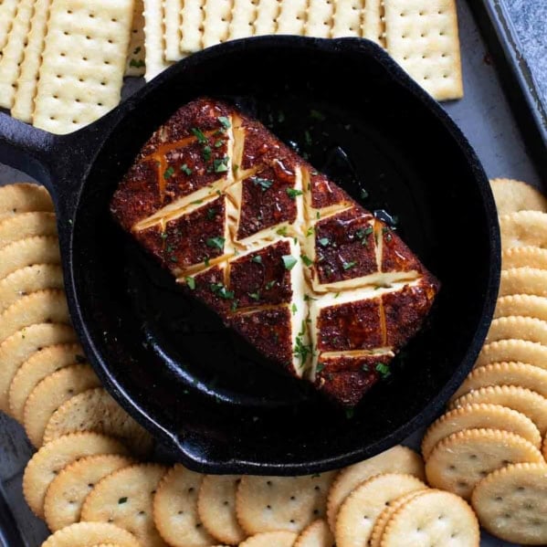 Smoked cream cheese in a cast iron dish, surrounded by crackers.