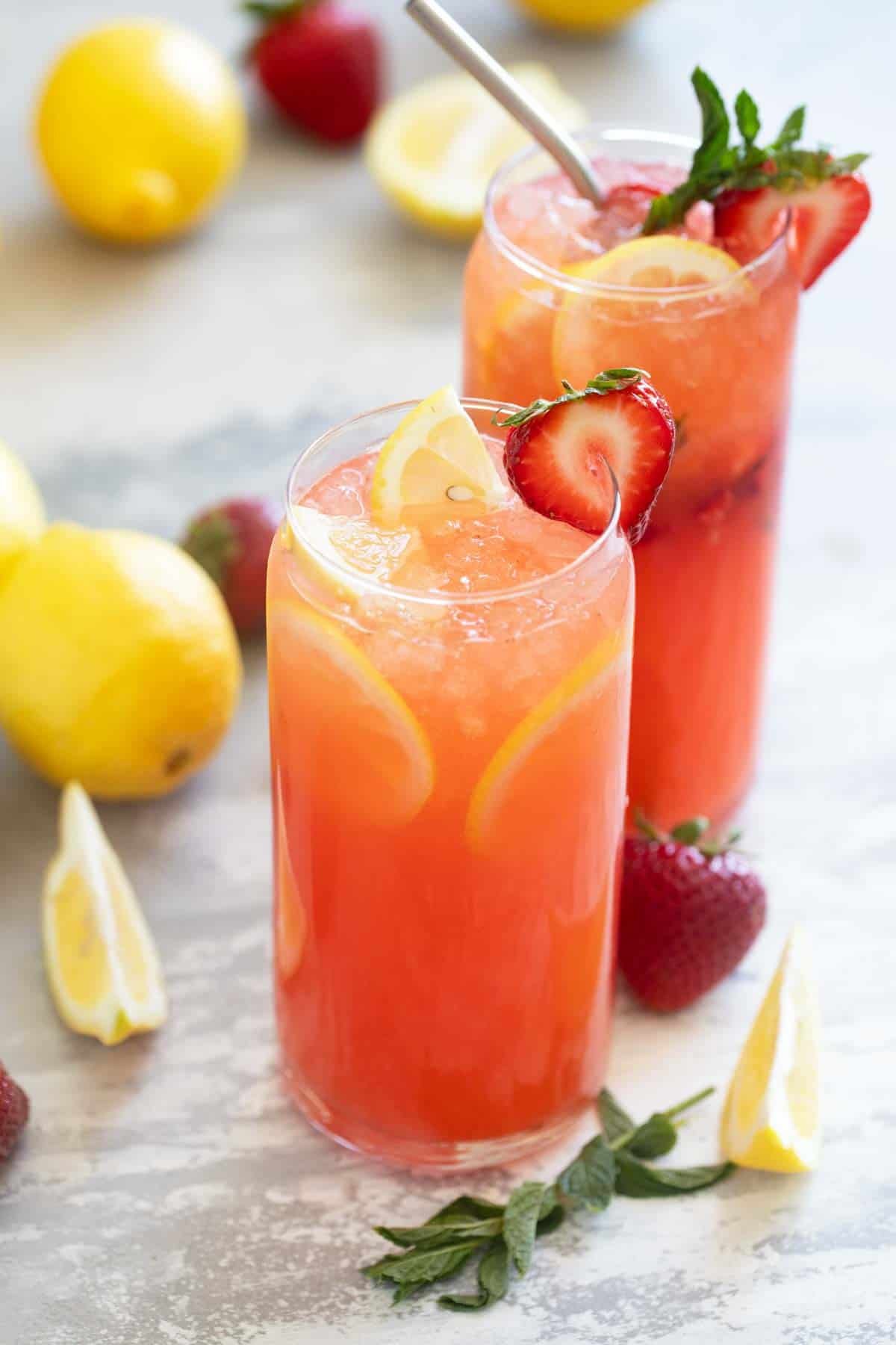 Glasses of strawberry lemonade with real lemon juice and strawberry syrup from scratch.