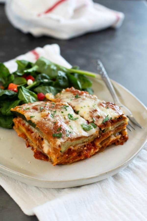 Slice of Zucchini Parmesan on a plate with a salad.