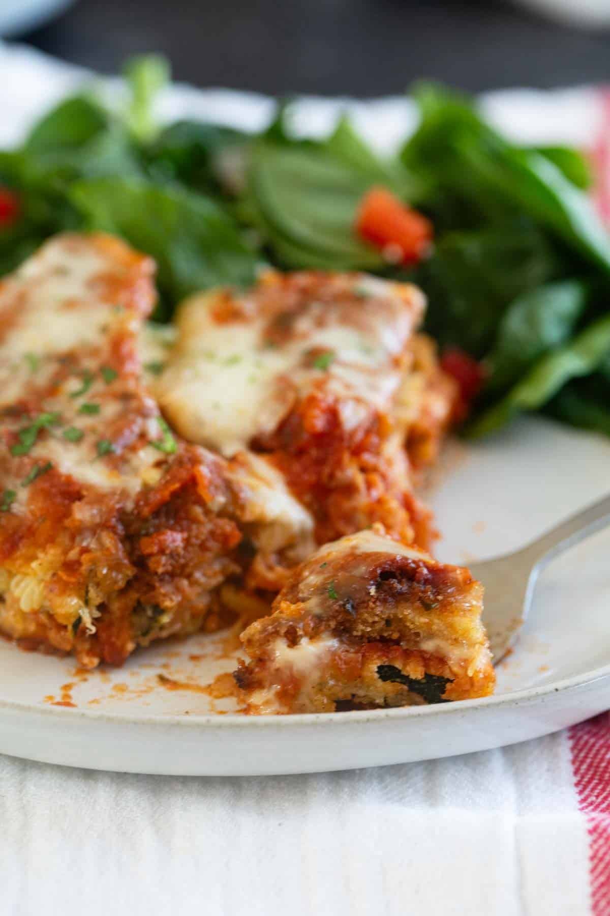 Slice of zucchini parmesan with a bite on a fork.