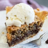 Slice of warm chocolate chip cookie pie with ice cream and a fork.