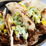 Plate with 3 Hawaiian Tacos topped with pineapple mango salsa and cilantro lime sauce.