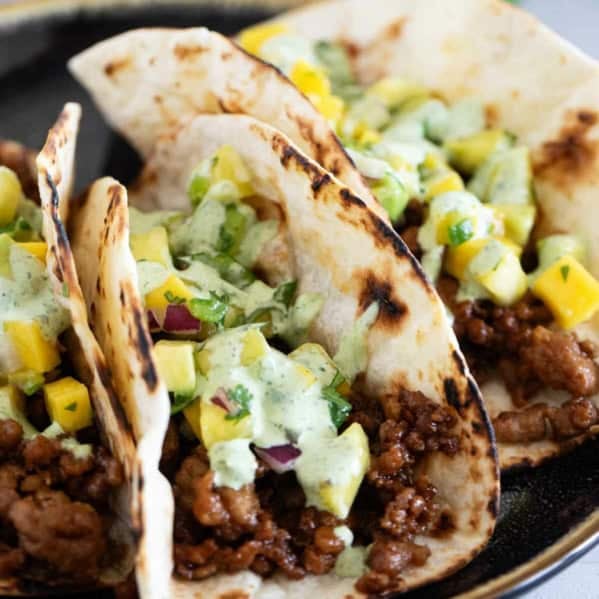Plate with 3 Hawaiian Tacos topped with pineapple mango salsa and cilantro lime sauce.