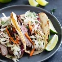 Thai Tacos with cilantro lime slaw and fresh lime slices.