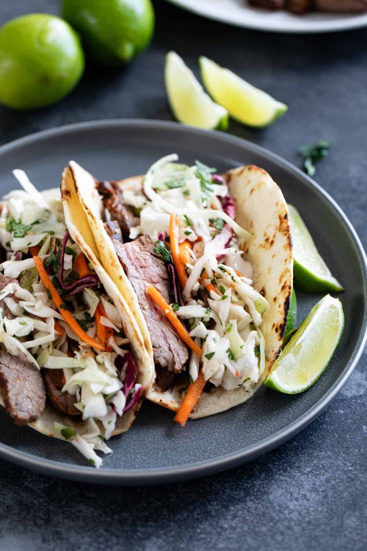 Thai Tacos with cilantro lime slaw and fresh lime slices.