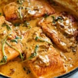 Tuscan Salmon in a skillet with sundried tomato cream sauce.