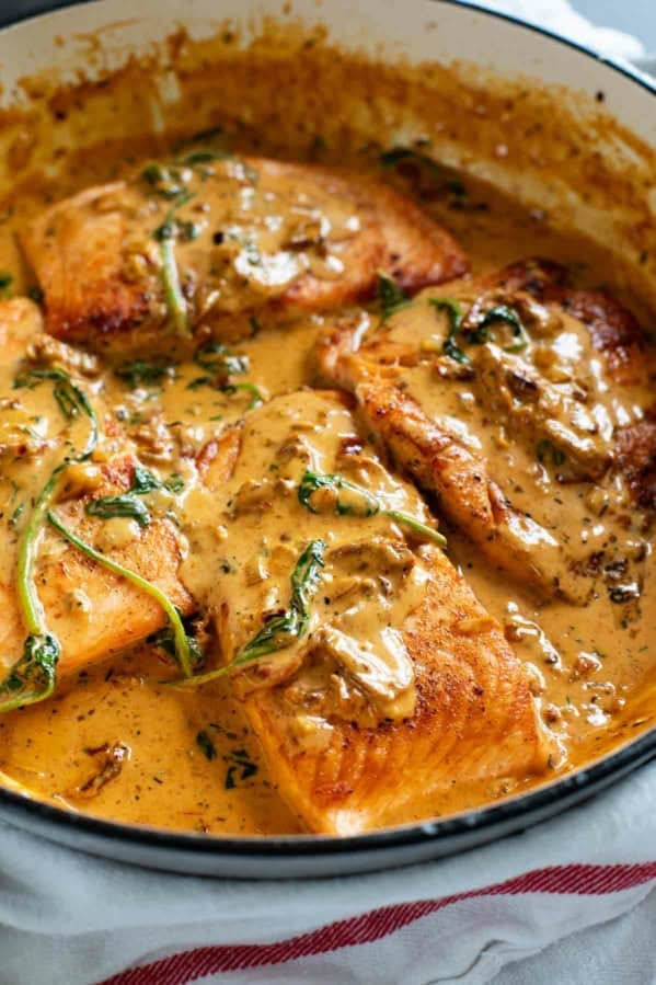 Tuscan Salmon in a skillet with sundried tomato cream sauce.