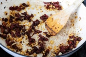 Sautéing onions and sun-dried tomatoes in a skillet.