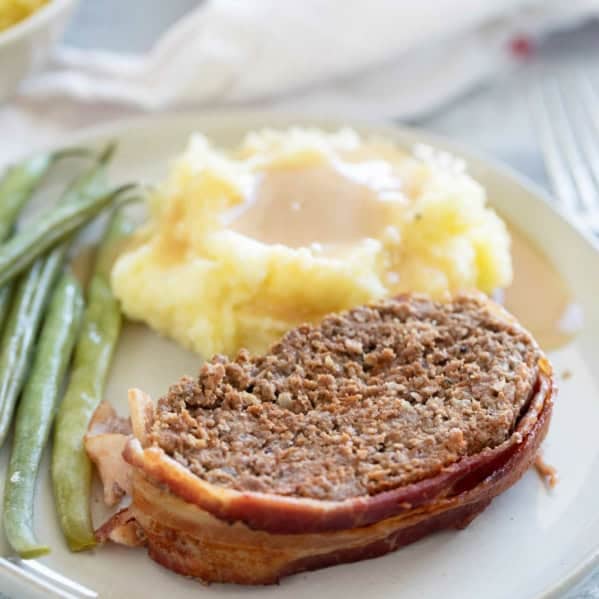 Serving of Bacon Wrapped Meatloaf with sides on a plate.