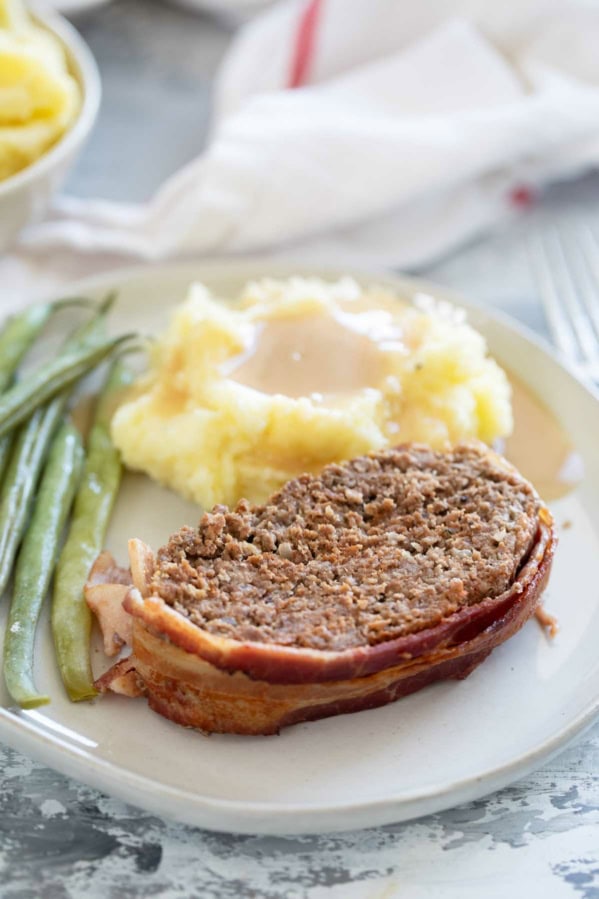 Serving of Bacon Wrapped Meatloaf with sides on a plate.