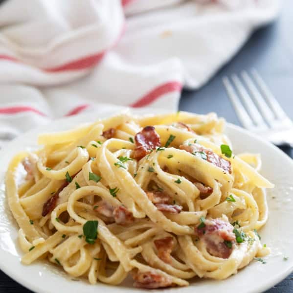 Plate with Brie Pasta with Bacon topped with parsley.