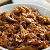 Bowl with Cafe Rio Sweet Pork on a cutting board.