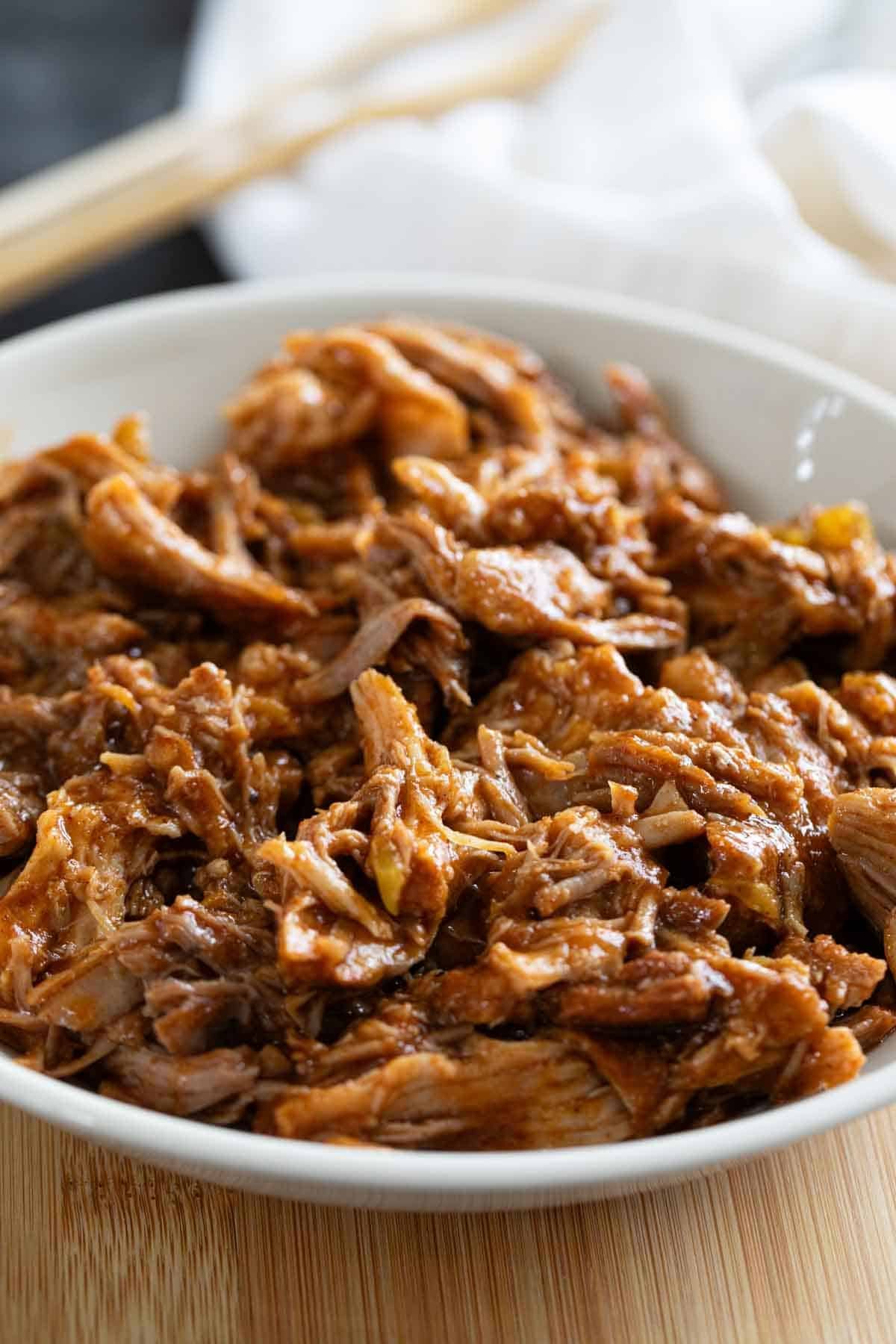 Bowl with Cafe Rio Sweet Pork on a cutting board.