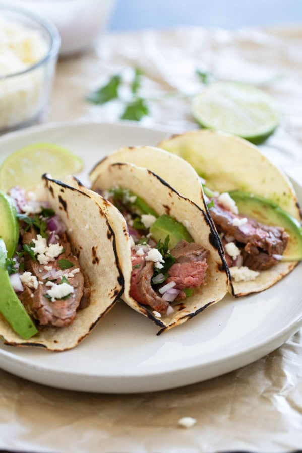 Flank Steak Tacos on corn tortillas on a plate.