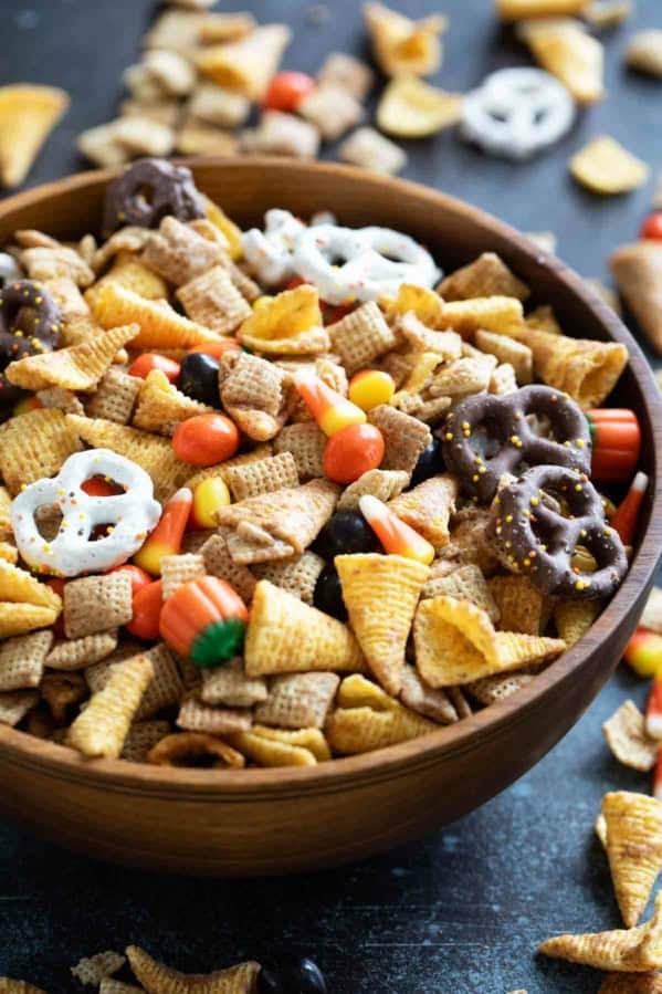 Wooden bowl filled with Halloween Chex mix.