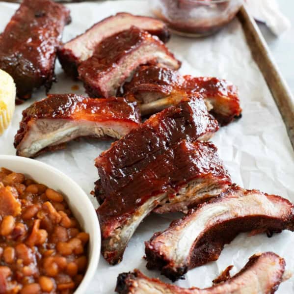 Smoked ribs on a tray with baked beans and corn muffins.