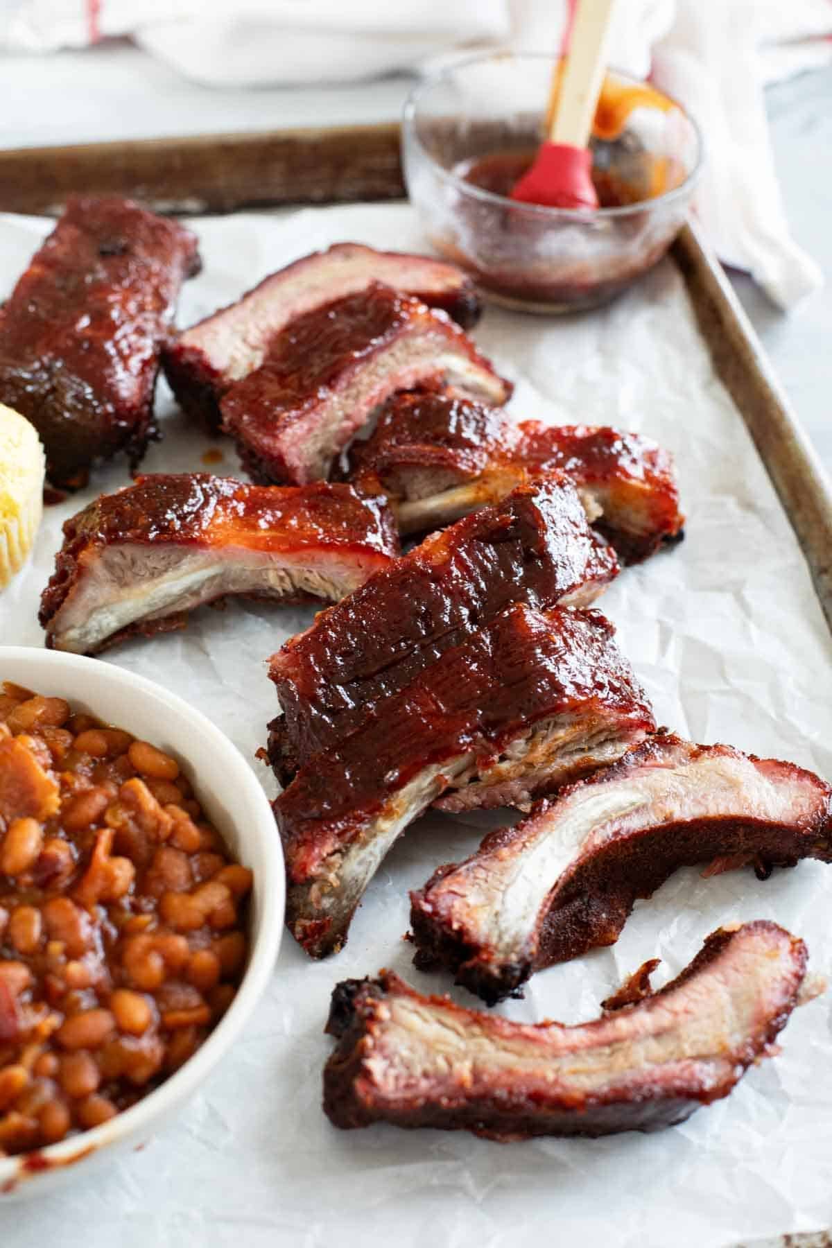 Smoked ribs on a tray with baked beans and corn muffins.