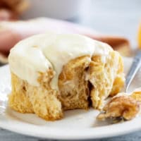 Sweet Potato Cinnamon Roll with a piece taken from it on a plate.