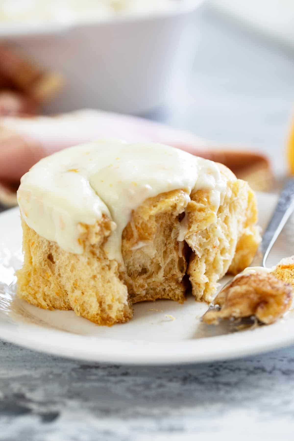 Sweet Potato Cinnamon Roll with a piece taken from it on a plate.