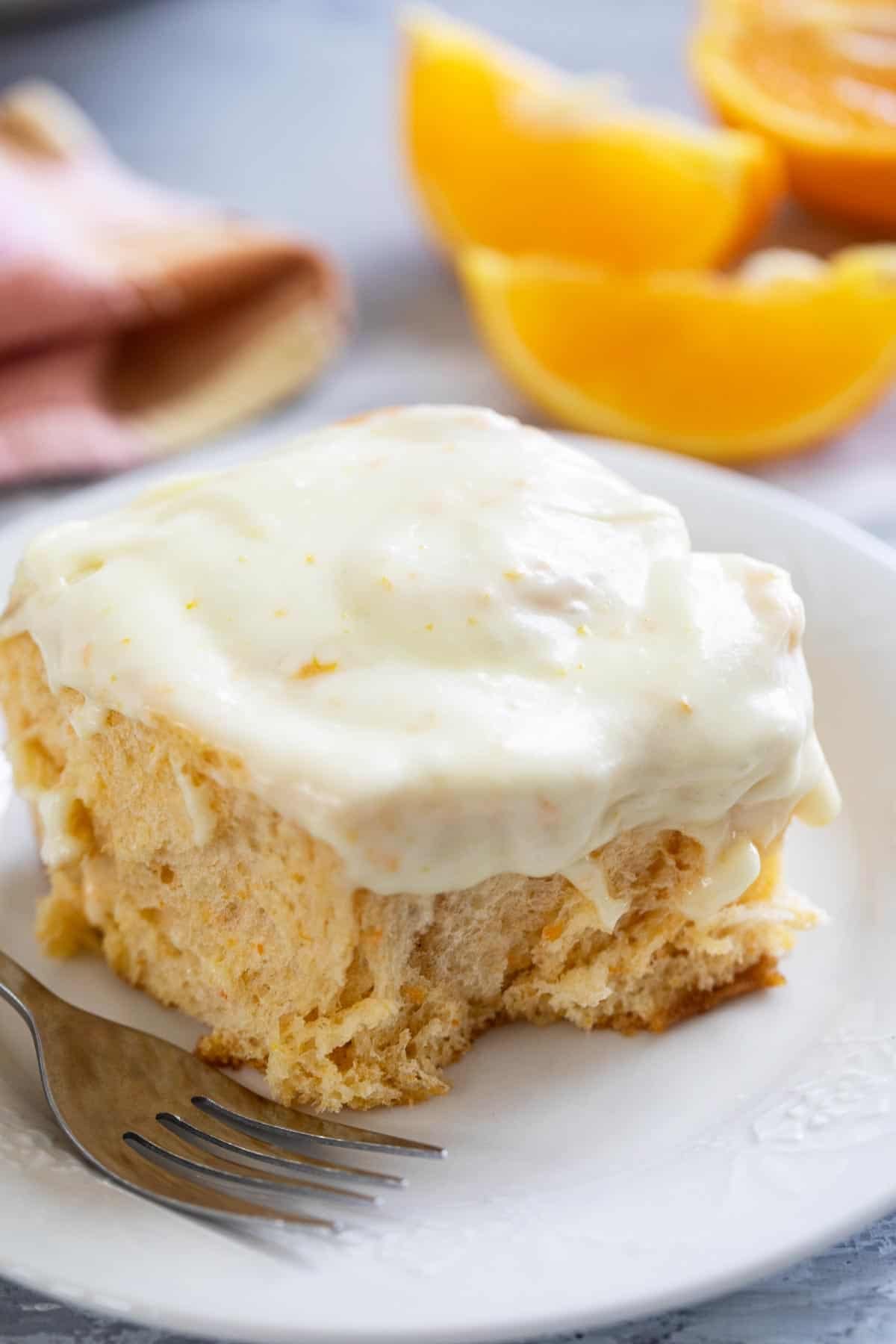 Sweet Potato Cinnamon Roll with Orange Cream Cheese Frosting on a plate with a fork.