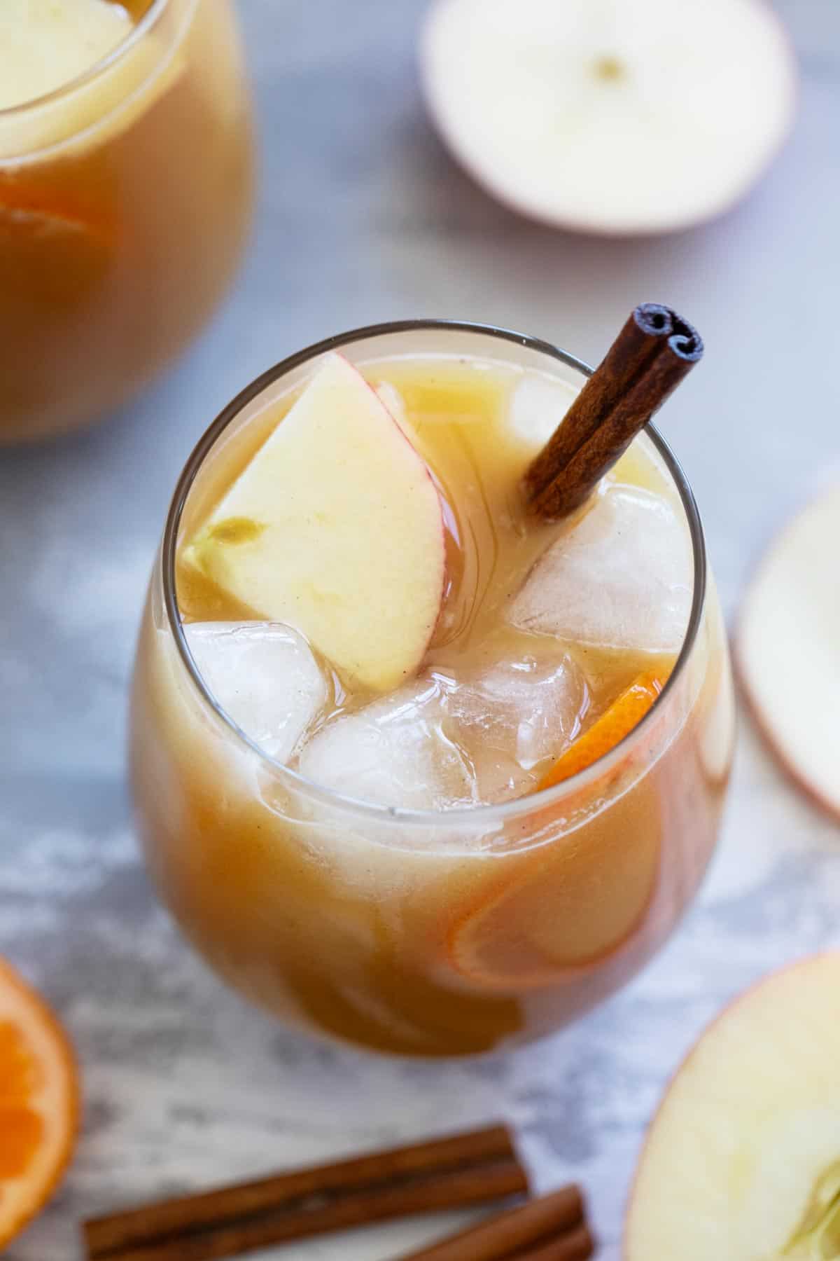 Glass of Apple Cider Punch with apple slices and a cinnamon stick.
