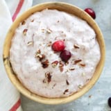 Cranberry Salad in a wooden bowl, topped with cranberries and chopped pecans.