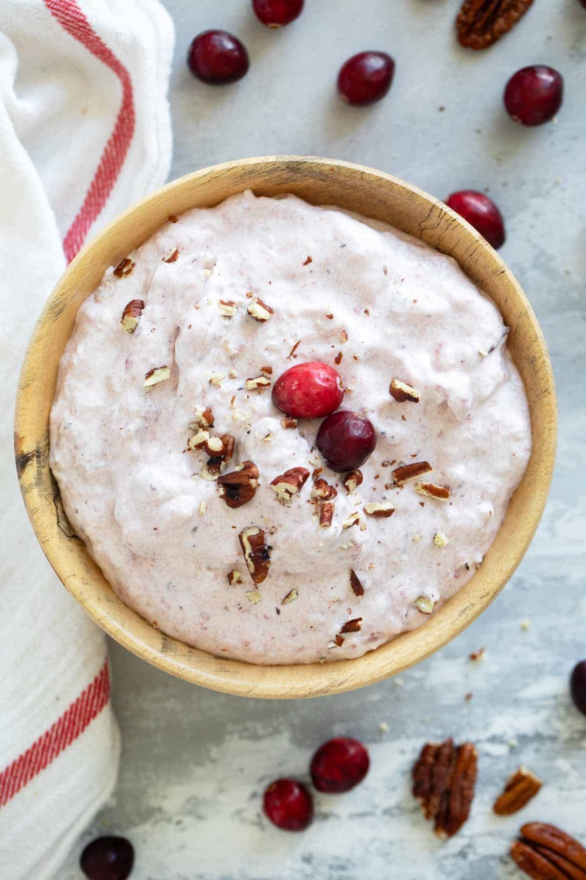 Cranberry Salad in a wooden bowl, topped with cranberries and chopped pecans.