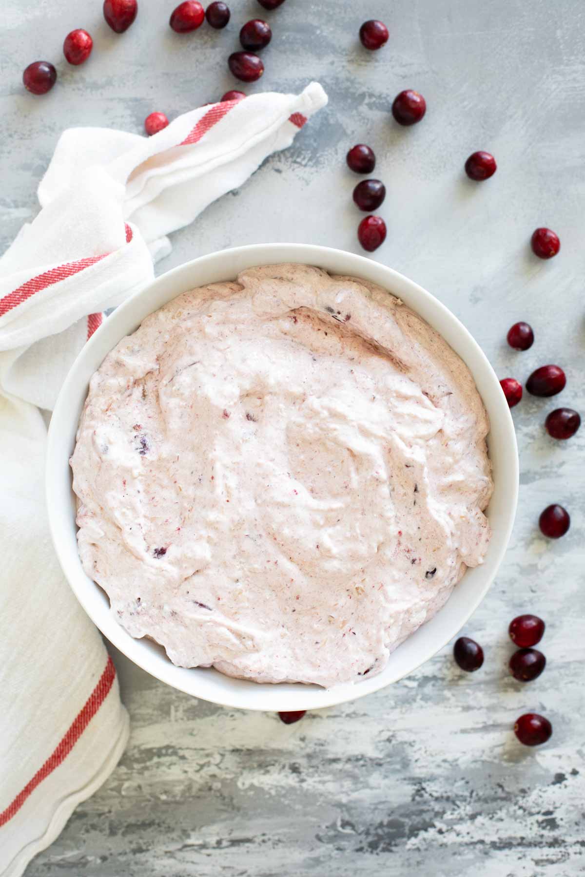 Serving bowl filled with Cranberry Salad, with cranberries around the bowl.