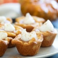 Mini Crescent Pumpkin Pies topped with whipped cream and cinnamon.