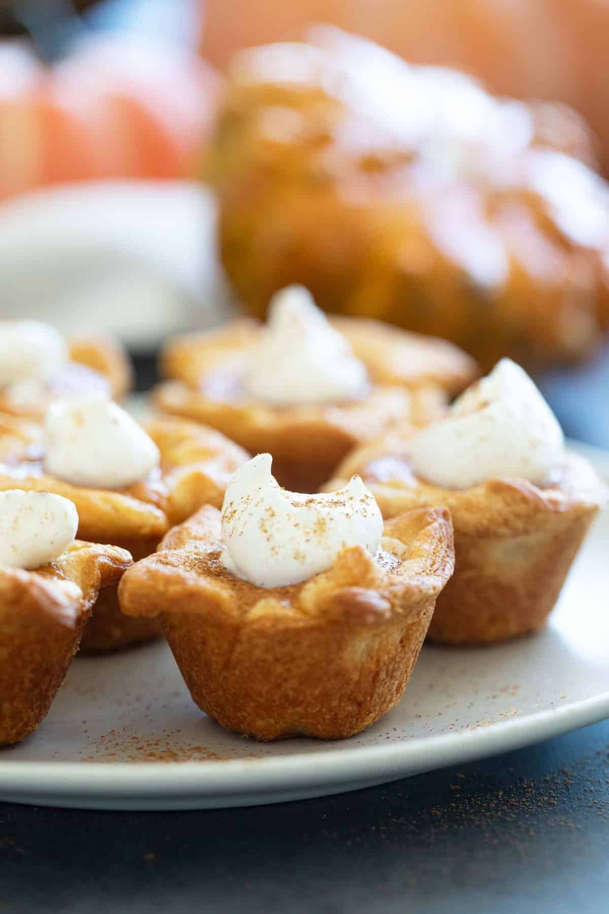 Mini Crescent Pumpkin Pies topped with whipped cream and cinnamon.