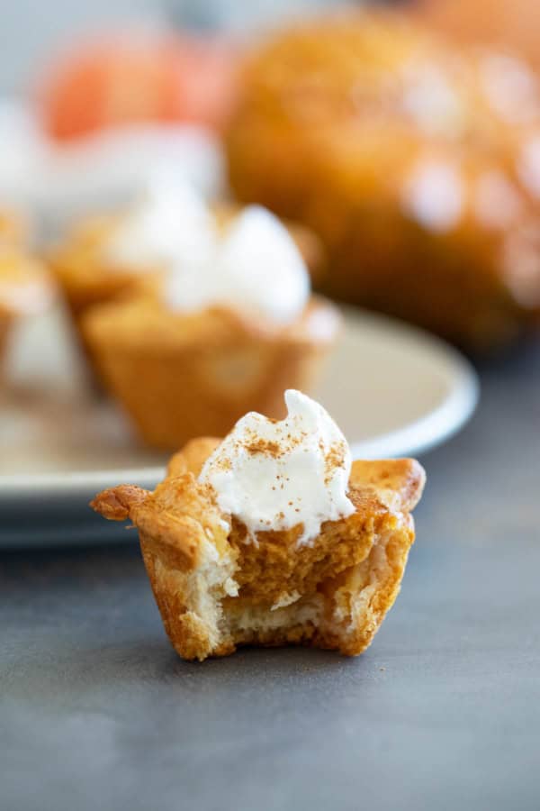A mini pumpkin pie made with a crescent roll crust with a bite taken from it.