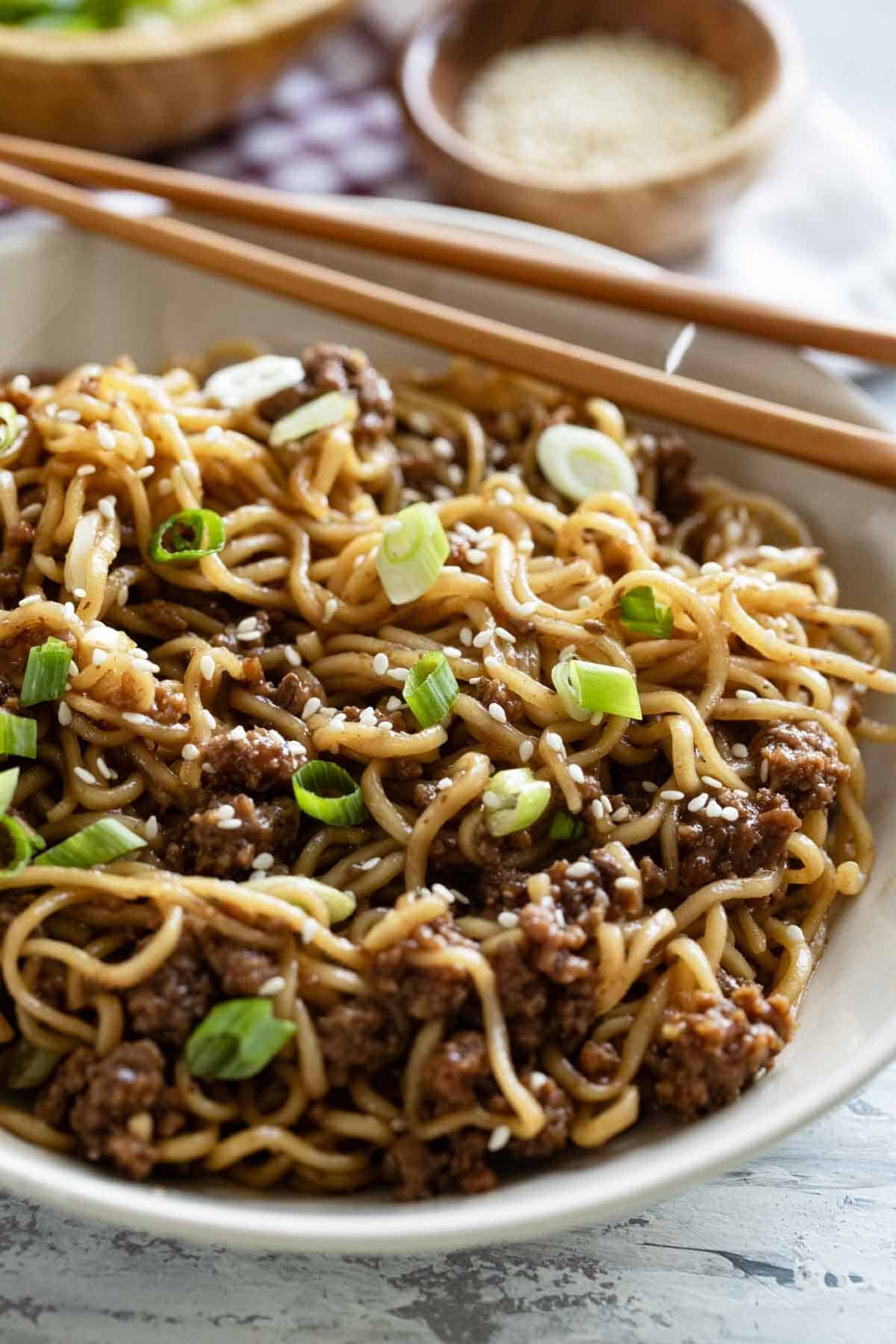 Bowl with Mongolian Ground Beef Noodles topped with green onion and sesame seeds.