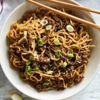Bowl filled with Mongolian Ground Beef Noodles with chopsticks on the side.