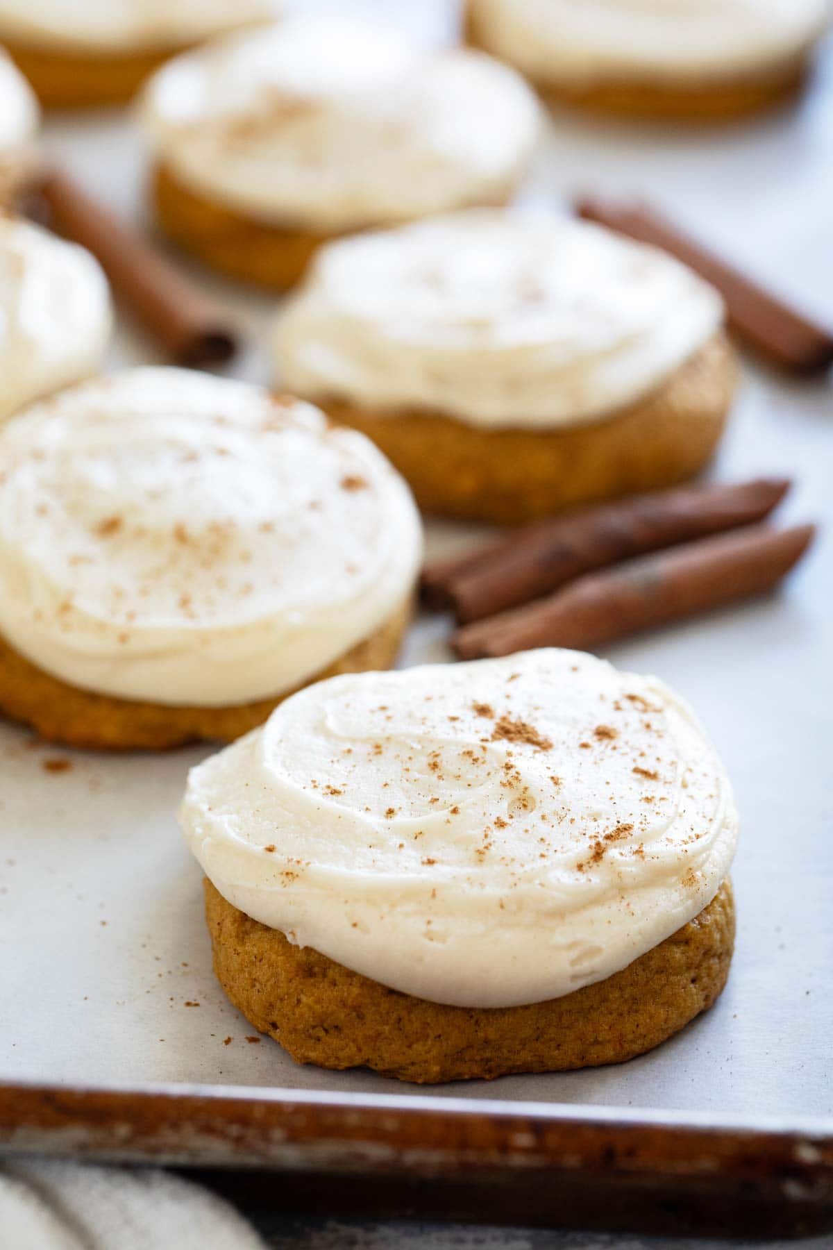 Soft Pumpkin Cookies with Cream Cheese Frosting with cinnamon dusted on top of cookies.