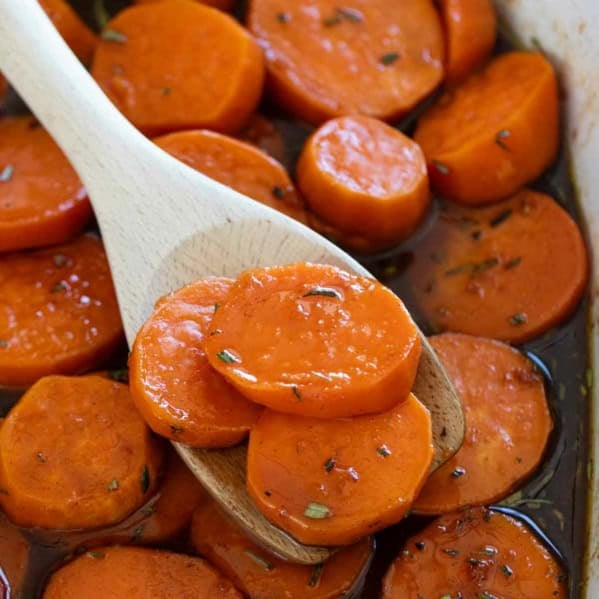 Scooping candied sweet potatoes with a wooden serving spoon.