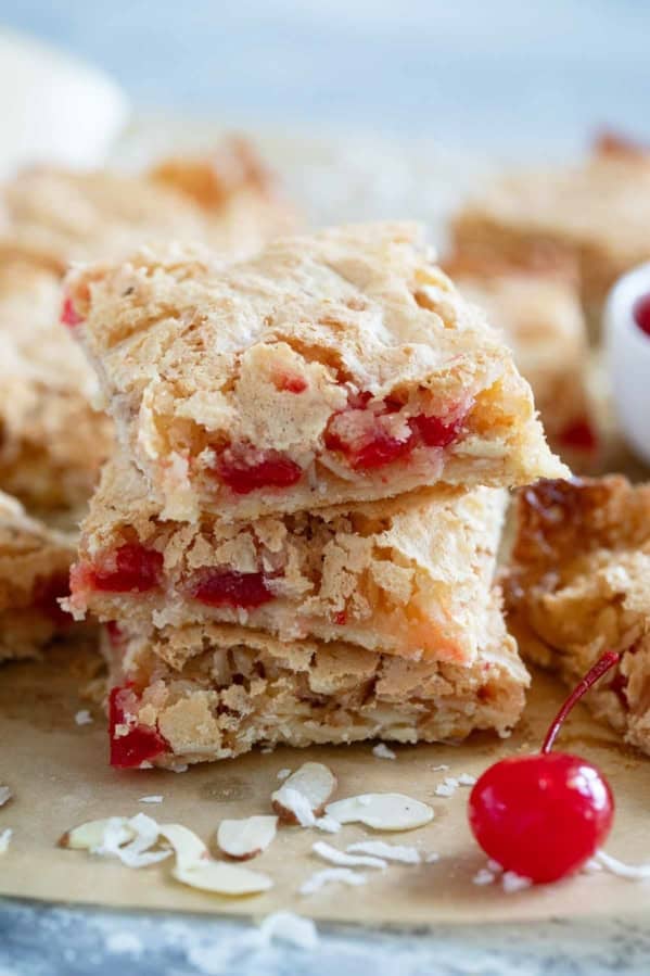 Three coconut cherry almond bars stacked on top of each other.
